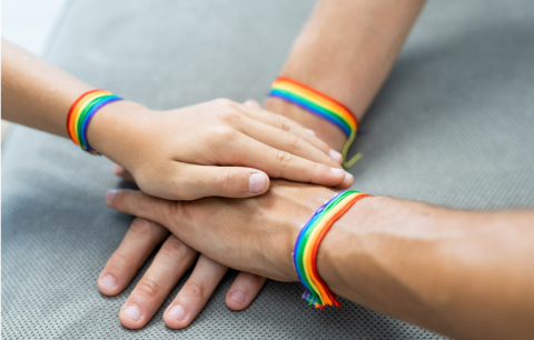 family hands stacked and wearing lgbtq rainbow bracelets