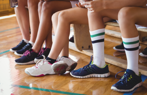 kids sitting on bench gym sneakers